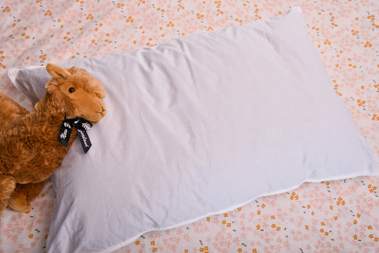 An adorable plush Alpaca toy resting on a cozy alpaca wool pillow.