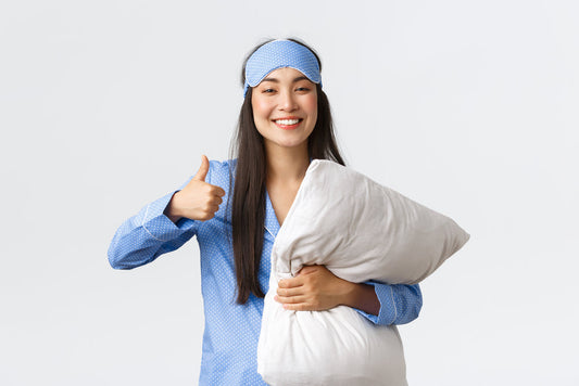 Cheerful pleased cute asian girl in blue pajama and sleeping mask, holding soft comfortable pillow and showing thumbs-up satisfied.